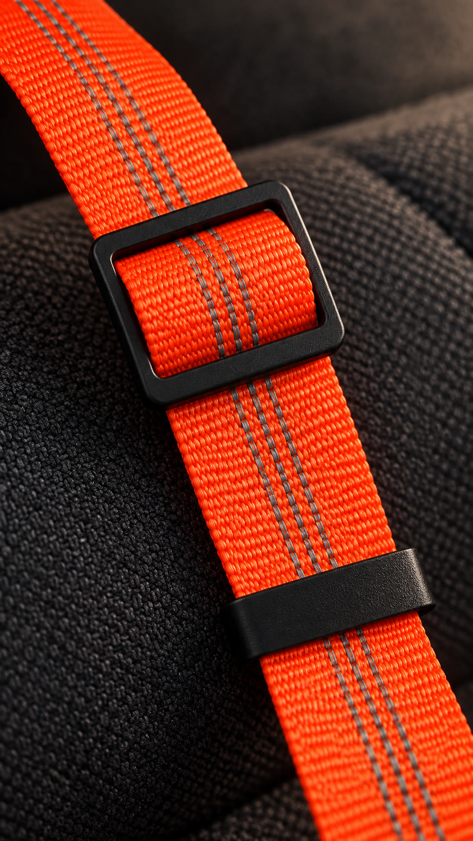 Close-up visualization of the black rectangular slider and keeper on orange woven webbing